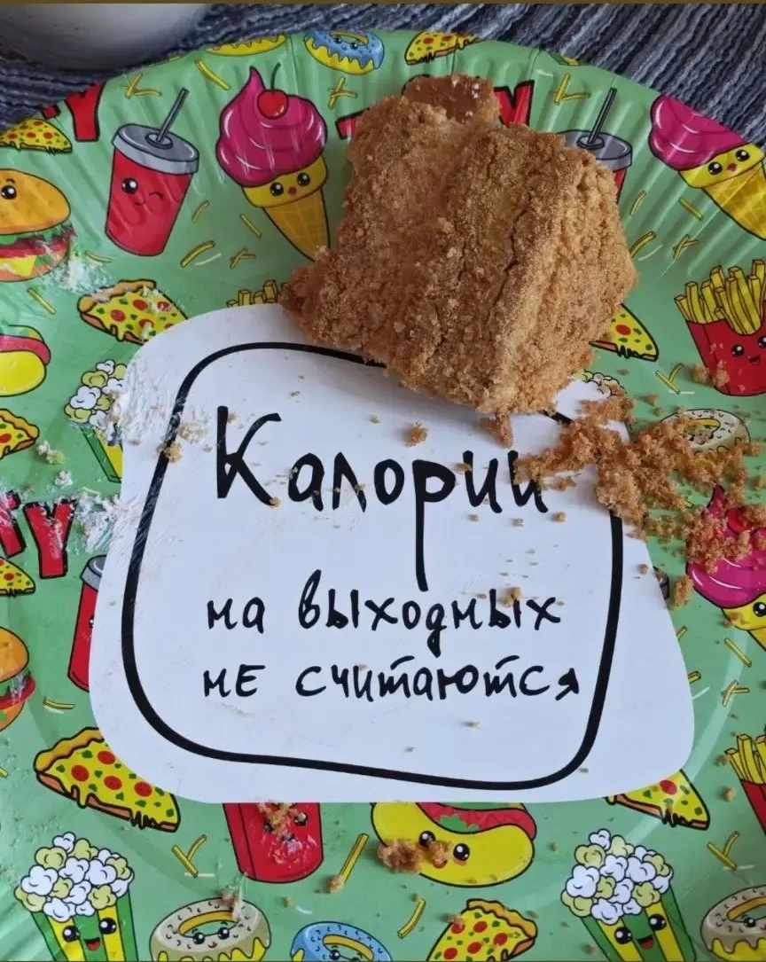 Кусок торта на тарелке со стикером «Калории на выходных не считаются»